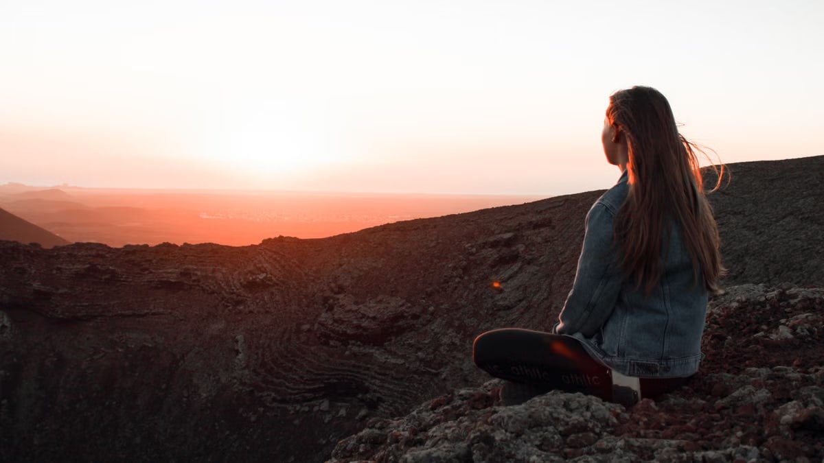 A woman watches the sunset over the rocky landscape, embracing the serene atmosphere.