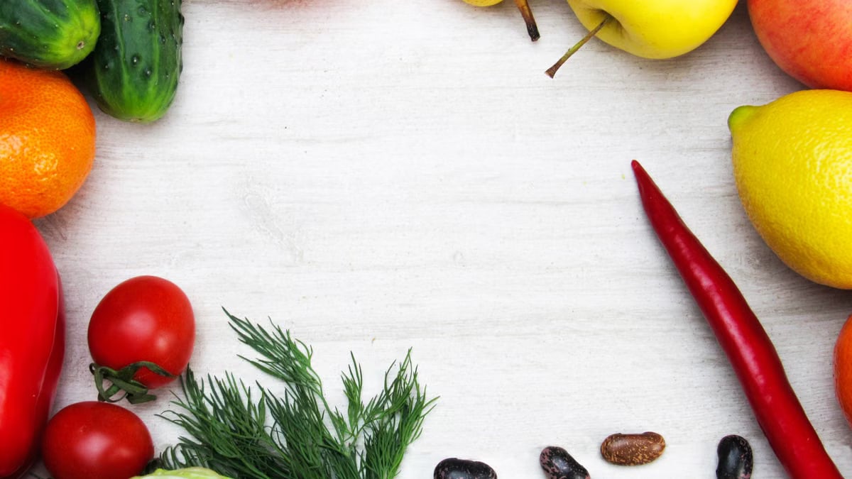 A vibrant flat lay of fresh fruits and vegetables with ample copy space on a white background.